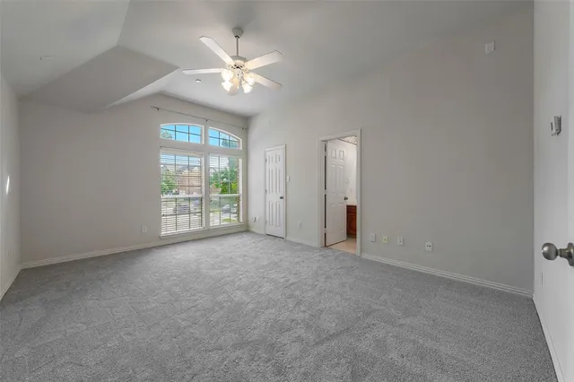 an empty room with windows and chandelier fan