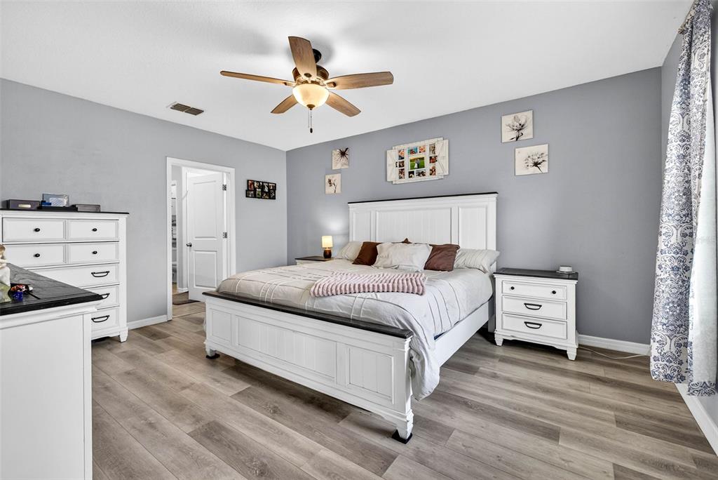 9616 Lemon Drop Loop Sun City Center, FL 33573 - Photo 21 of 53 a bedroom with a large bed and a chandelier