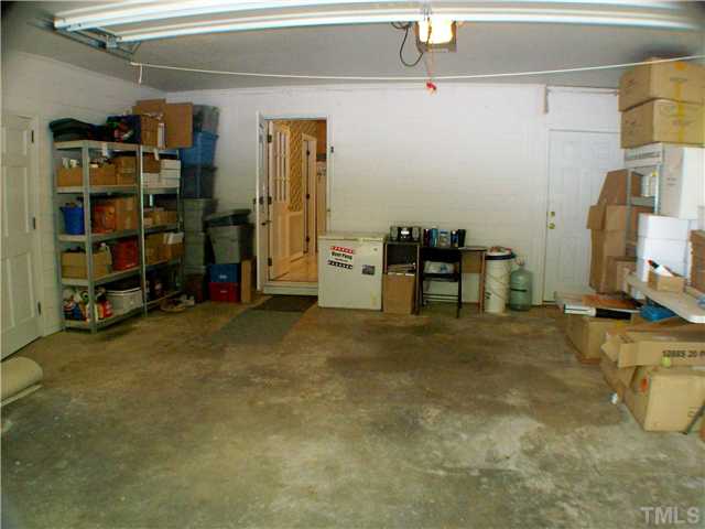 8805 Red Oak Court Raleigh, NC 27613 - Photo 12 of 12 Oversized one car garage. Door to the left leads to storage room 4x21. Door in back left leads to kitchen entry. Door in back right leads to rocking chair front portch. Storage shelves on left convey with house! Two windows are on the right side of garage