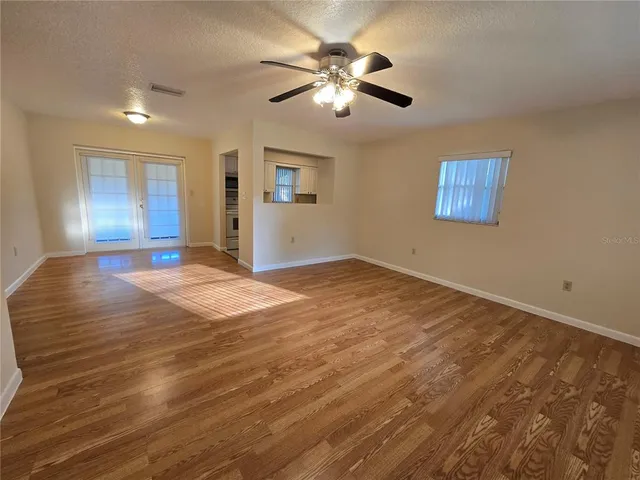a view of an empty room with window and wooden floor