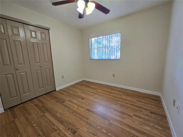 an empty room with wooden floor chandelier fan and windows