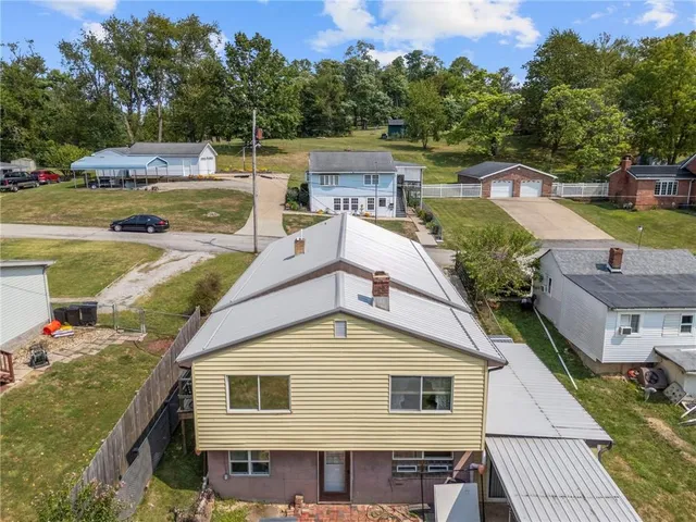 aerial view of a house with a yard and large tree