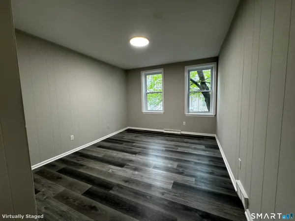a view of an empty room with wooden floor and a window
