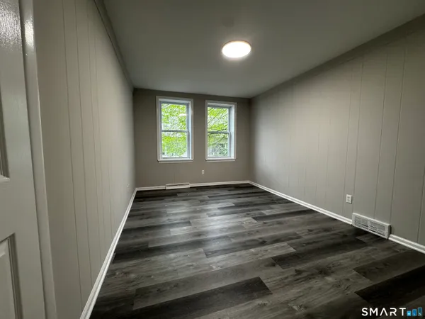 an empty room with wooden floor and window