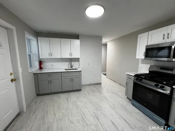 a kitchen with granite countertop a sink cabinets and stainless steel appliances