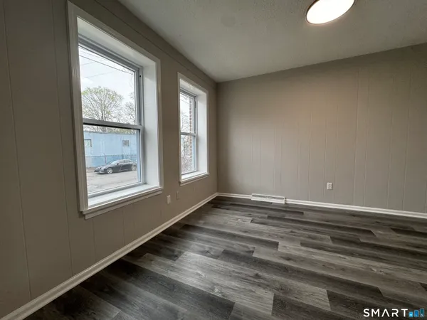 a view of an empty room with wooden floor and a window