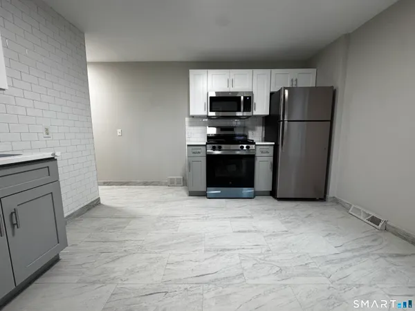 a kitchen with stainless steel appliances granite countertop a refrigerator a stove a sink and a microwave