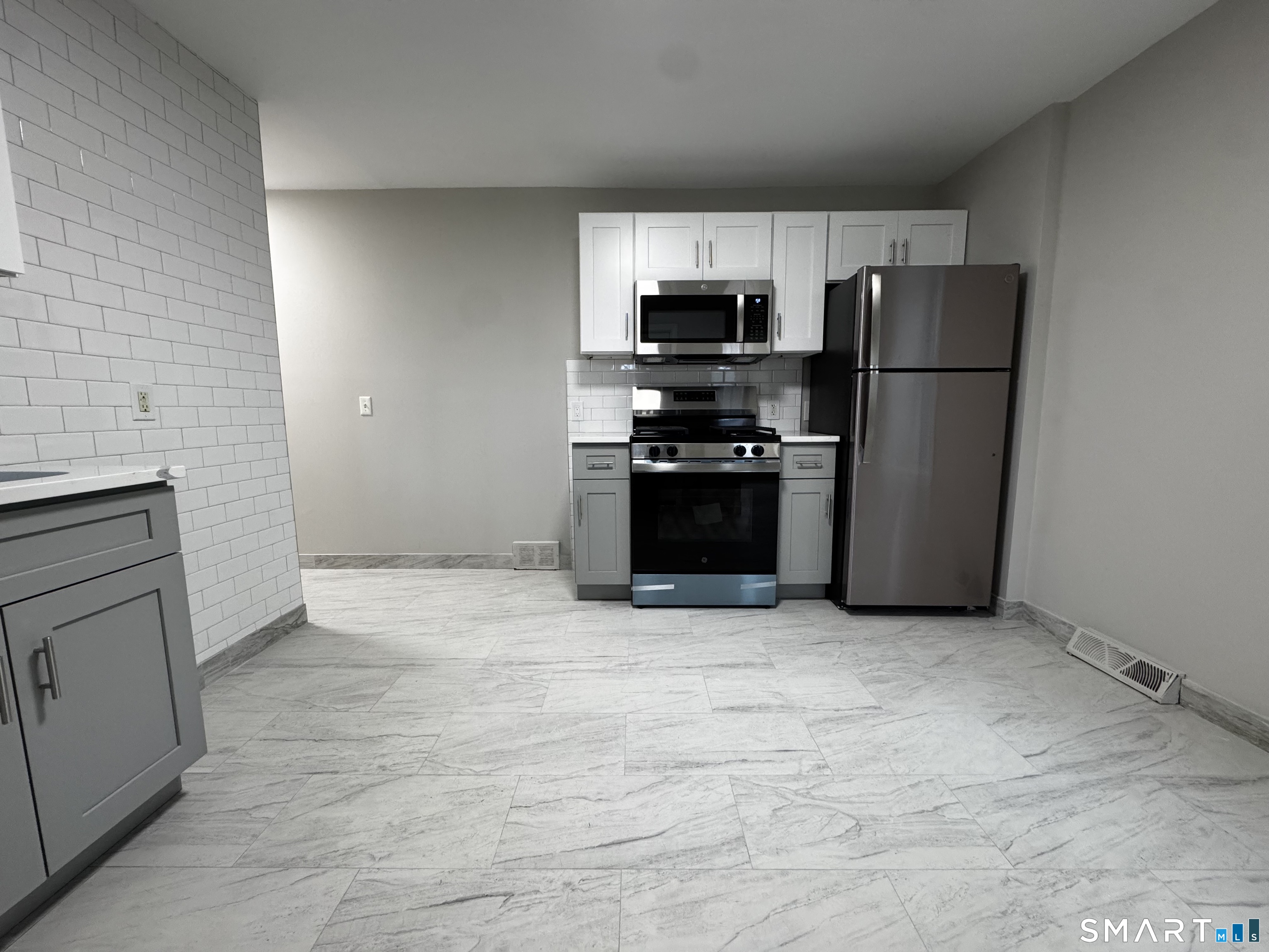 45-51 Cowles Street, Unit 45 Bridgeport, CT 06607 - Photo 3 of 33 a kitchen with stainless steel appliances granite countertop a refrigerator a stove a sink and a microwave