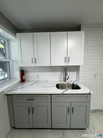 a kitchen with white cabinets and sink