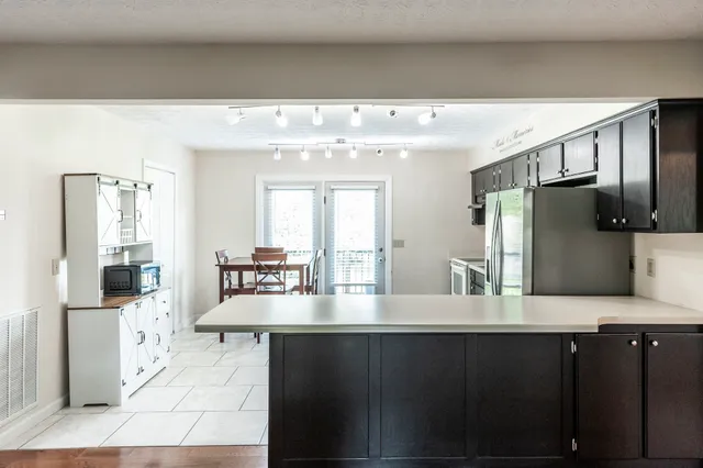a kitchen with kitchen island granite countertop a refrigerator and cabinets
