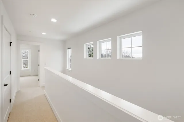 a view of hallway with window and wooden floor