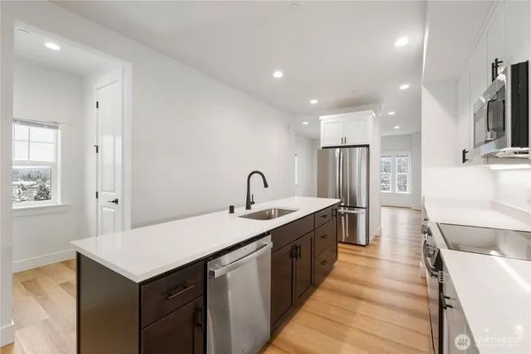 a kitchen with a sink a counter top space stainless steel appliances and cabinets