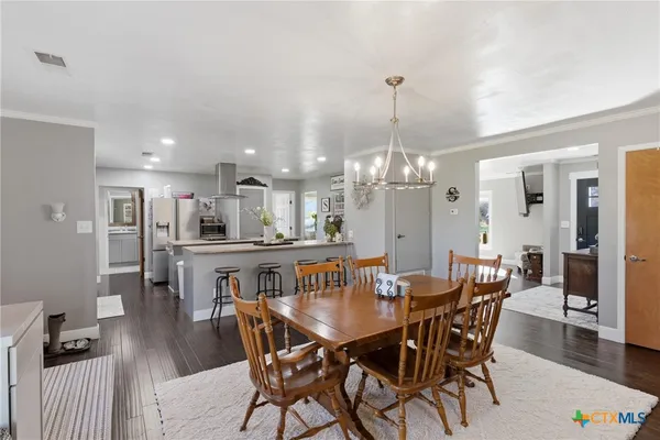 a view of a dining room and livingroom with furniture wooden floor a chandelier