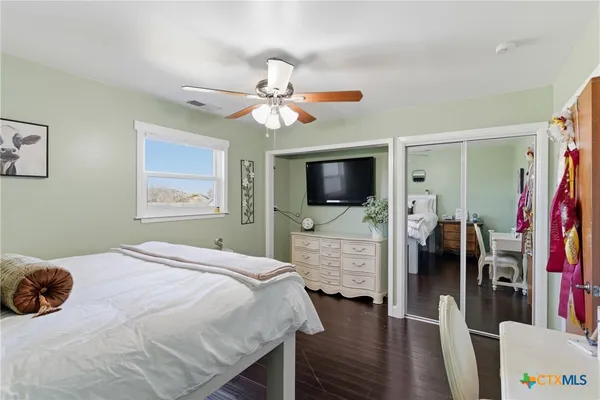 a bedroom with a bed and a flat tv screen on dresser