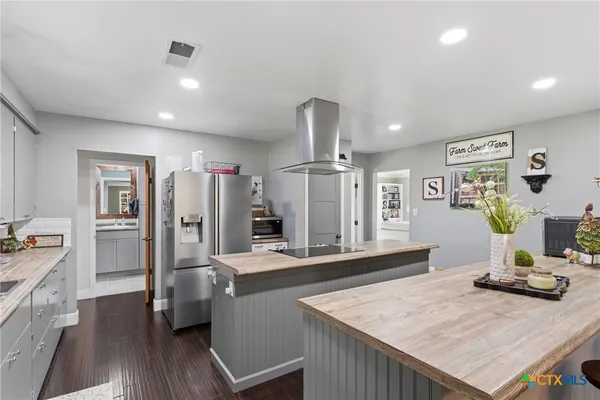 a kitchen with stainless steel appliances kitchen island granite countertop a refrigerator a stove and a sink with wooden floor