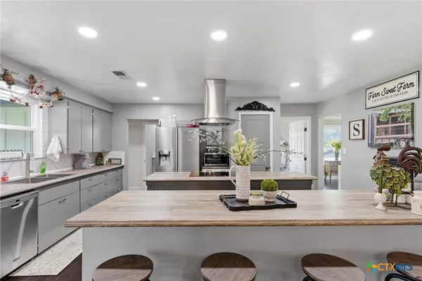 a kitchen with kitchen island granite countertop a sink a counter top space and cabinets