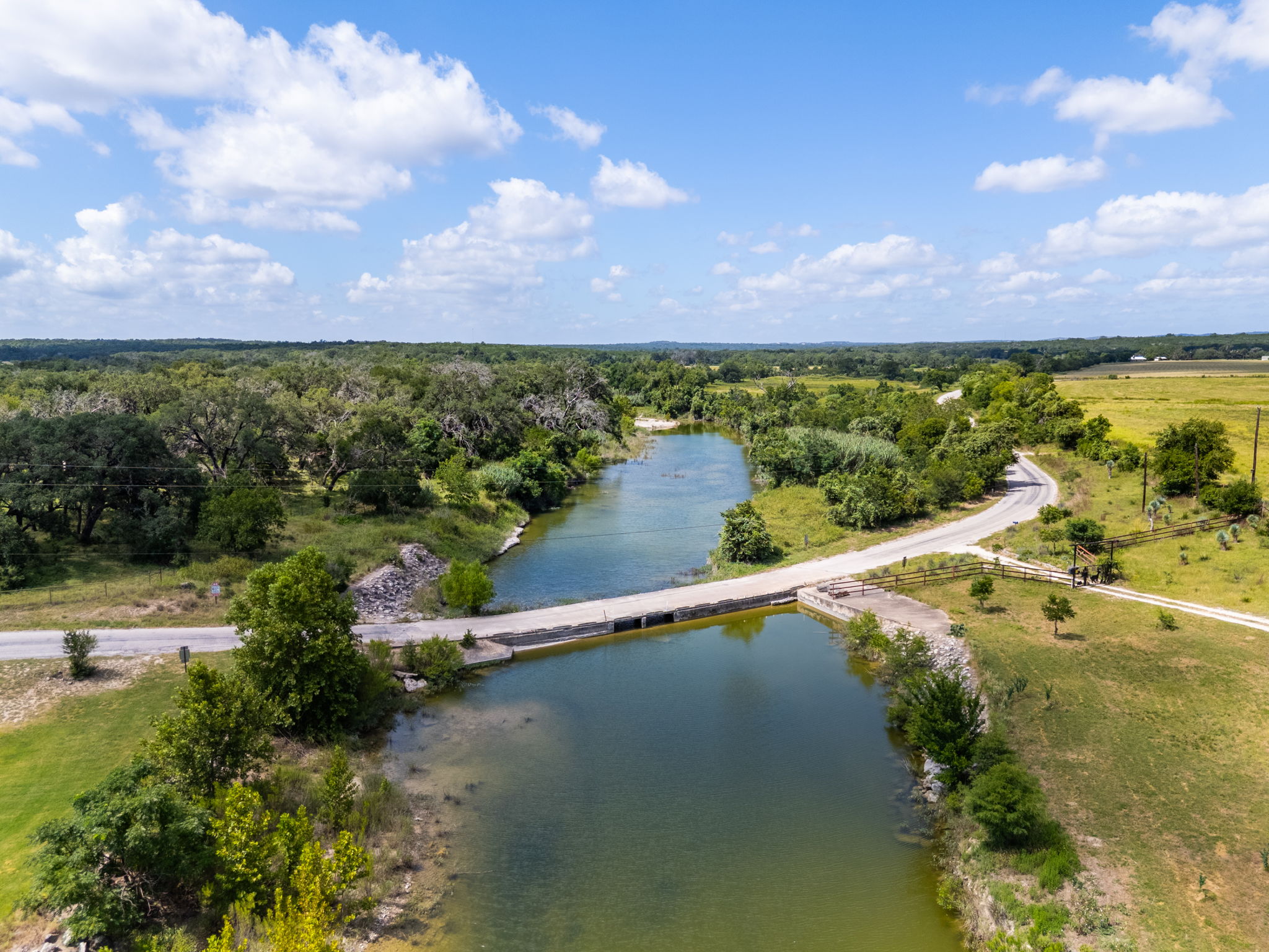 5385 Ranch Road 165 Blanco, TX 78606 - Photo 38 of 40 A picturesque aerial perspective reveals a serene river winding through a lush, verdant landscape under a bright sky.
