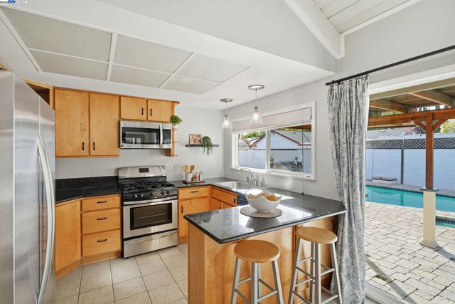 a kitchen with granite countertop a sink a stove and wooden cabinets