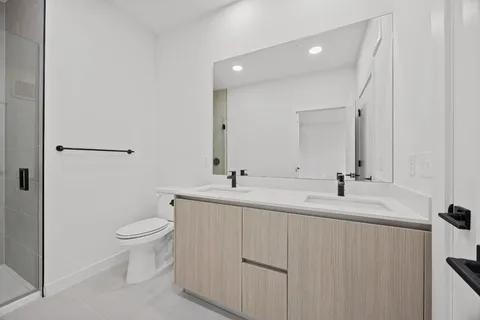 a bathroom with a granite countertop sink a toilet and a shower