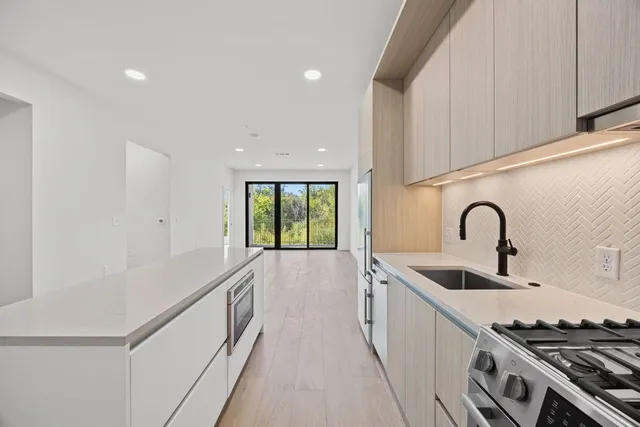 a kitchen with sink a stove and white cabinets with wooden floor