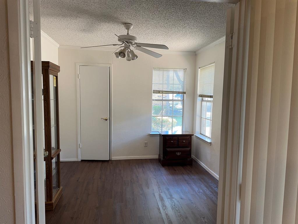 5300 Keller Springs Road, Unit 1090 Dallas, TX 75248 - Photo 3 of 10 Spare room with a textured ceiling, dark wood-type flooring, crown molding, ceiling fan, and baseboards