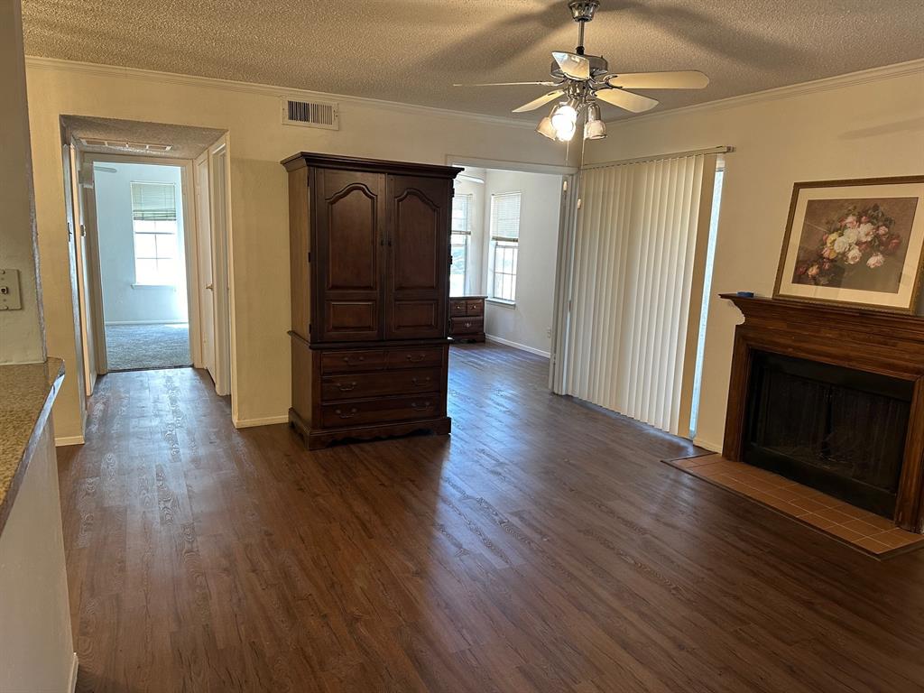 5300 Keller Springs Road, Unit 1090 Dallas, TX 75248 - Photo 8 of 10 Living area featuring crown molding, ceiling fan, a textured ceiling, dark wood-style floors, and a fireplace