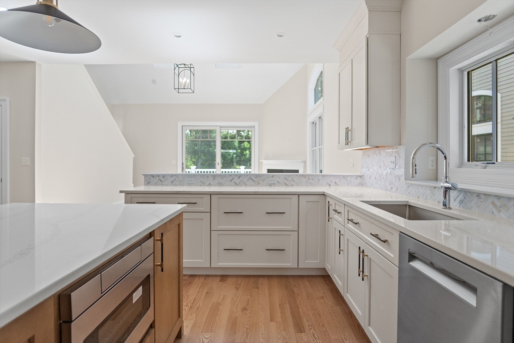 18 Talbot Lane, Unit 18 Reading, MA 01867 - Photo 11 of 33 a kitchen with a sink dishwasher a stove and white cabinets with wooden floor