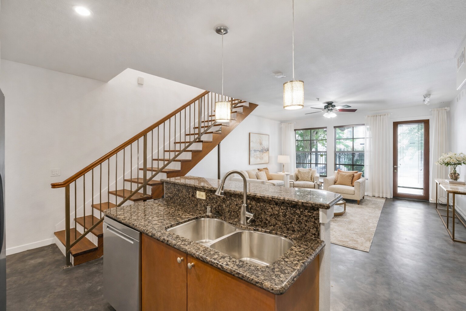 2216 Chenevert Street, Unit 6 Houston, TX 77003 - Photo 2 of 29 Condo #6: Sleek open-concept layout showcasing modern floating stairs, polished concrete floors, granite countertops, and pendant lighting, flowing effortlessly into the living area with direct access to the private patio and quiet street parking. Image virtually staged.
