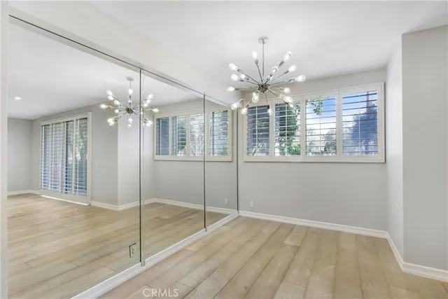 a view of an empty room with chandelier fan and kitchen view