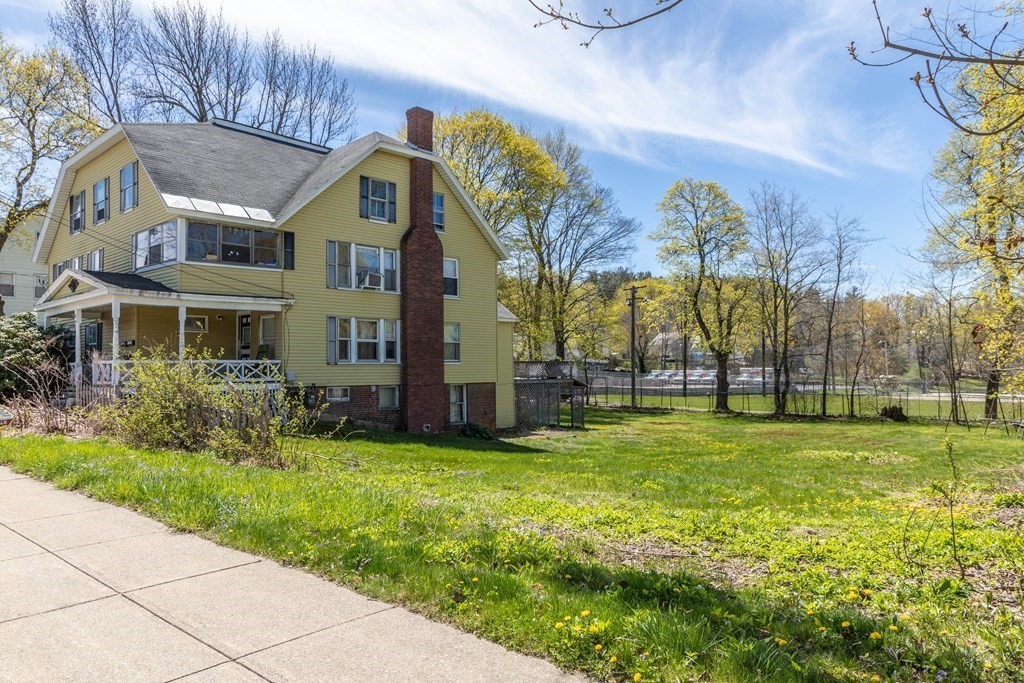 a view of a house with a big yard and large trees