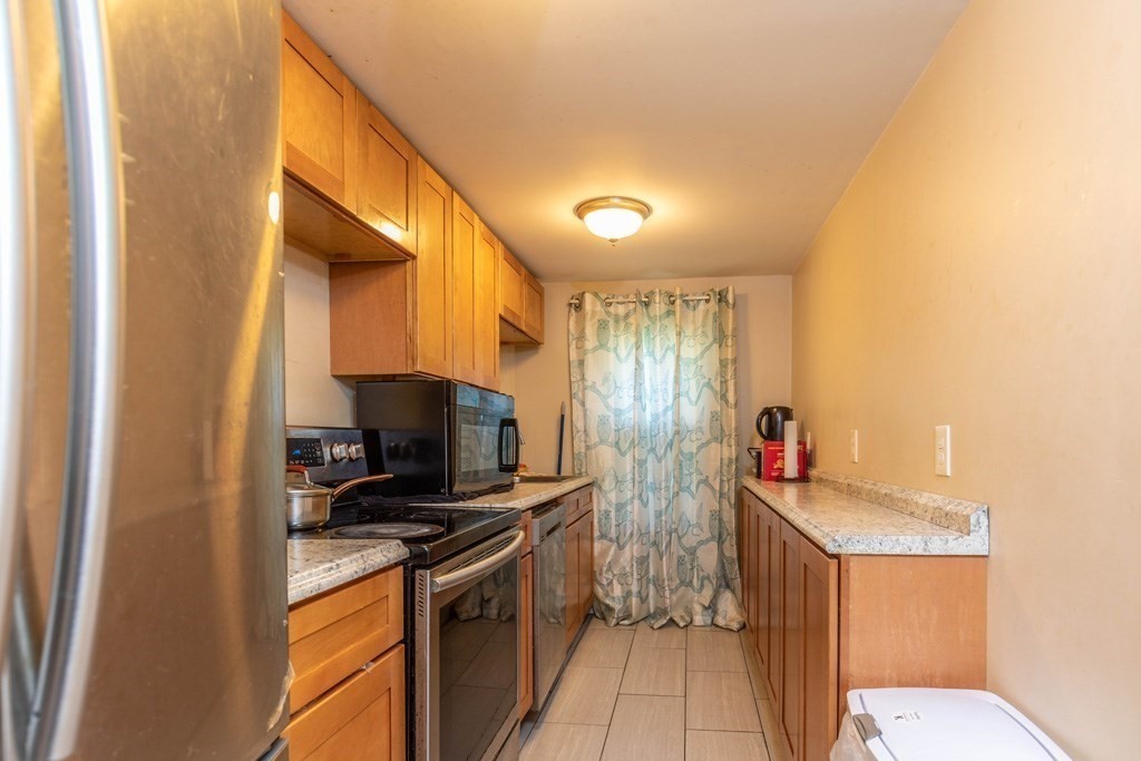 48 West Broadway Gardner, MA 01440 - Photo 11 of 21 a kitchen with stainless steel appliances a sink a stove top oven a chimney and a refrigerator