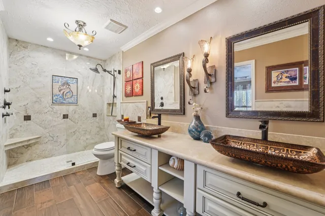 a spacious bathroom with a granite countertop sink a toilet a mirror and shower