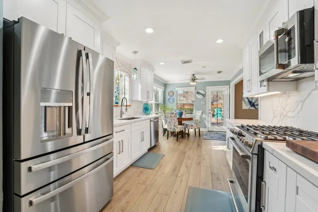 a kitchen with stainless steel appliances granite countertop a stove top oven a refrigerator a dining table and chairs with wooden floor