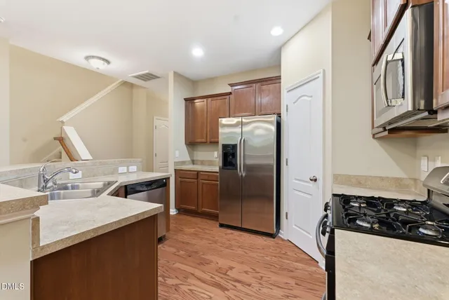 a kitchen with stainless steel appliances granite countertop a refrigerator a sink a stove and oven