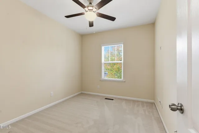 an empty room with a window and a fan