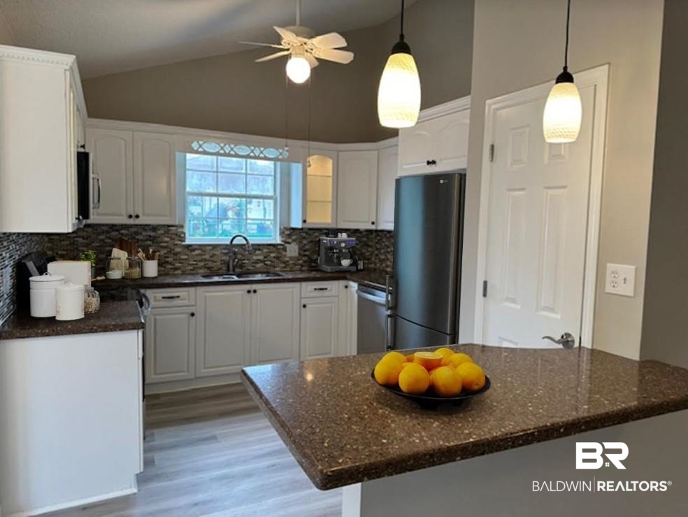 1512 North Cedar Street Foley, AL 36535 - Photo 5 of 13 Kitchen featuring light hardwood / wood-style flooring, appliances with stainless steel finishes, sink, white cabinetry, and lofted ceiling