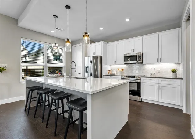 a kitchen with kitchen island granite countertop white cabinets and stainless steel appliances