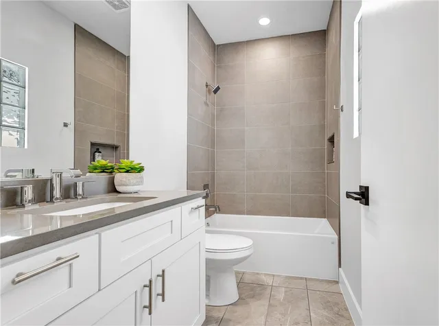 a bathroom with a granite countertop sink a toilet a mirror a bathtub and shower