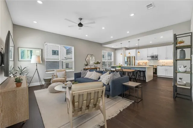 a living room with furniture kitchen view and a wooden floor