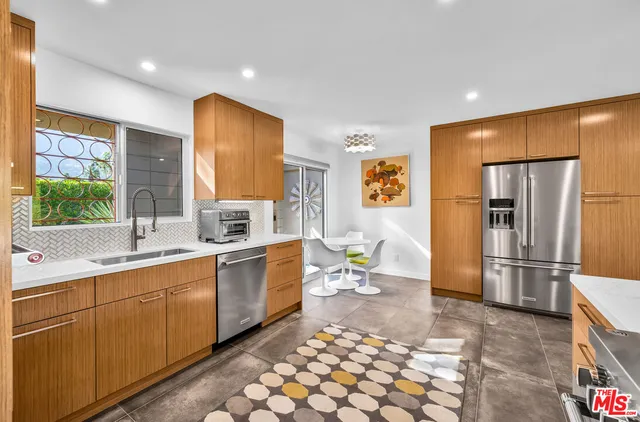 a view of a kitchen with kitchen island stainless steel appliances wooden floor dining table and chairs