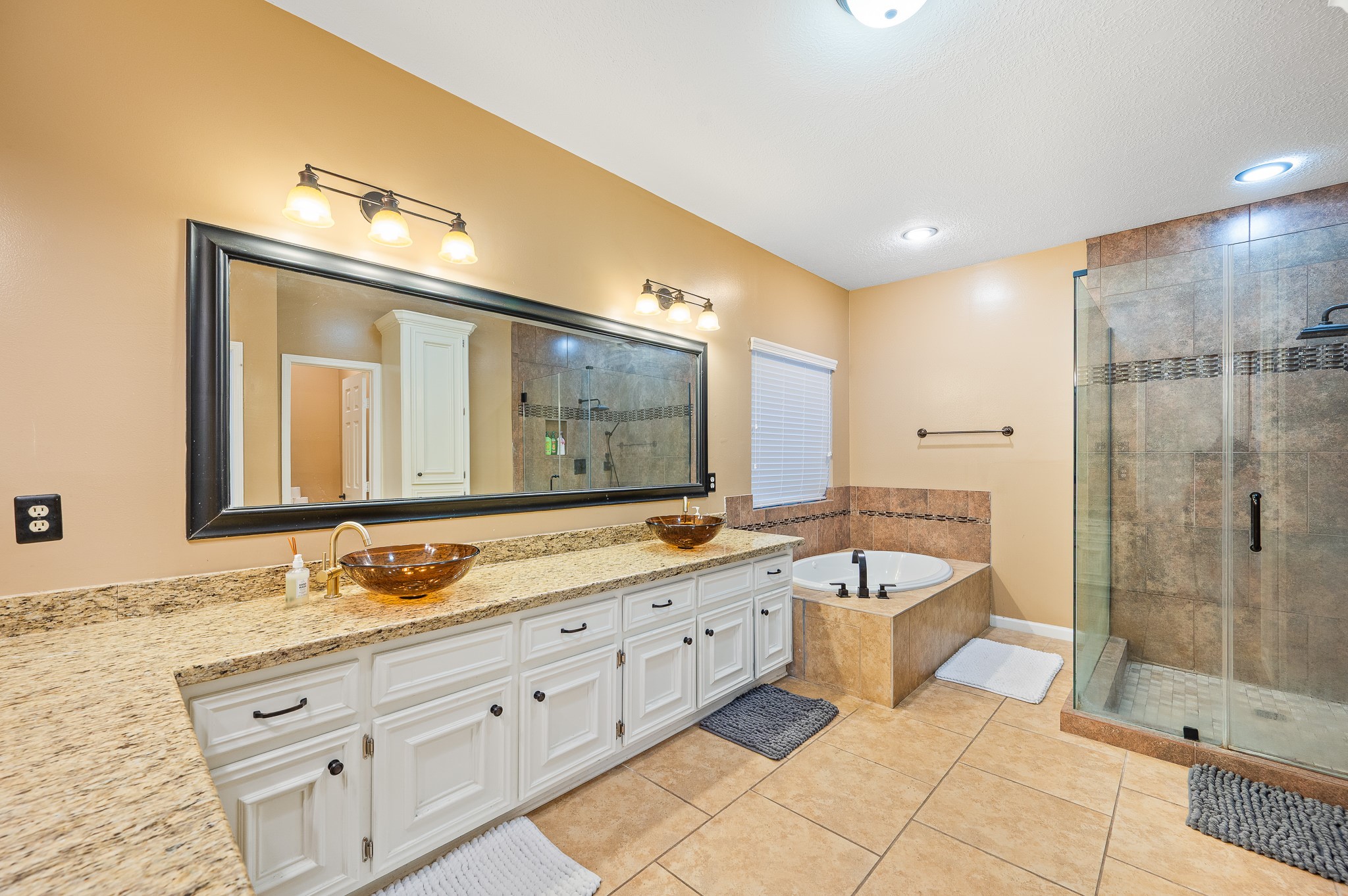 8111 Morningbrook Court Spring, TX 77379 - Photo 23 of 46 The spa-inspired primary bathroom features granite counters, double sinks, a vanity space, and a separate tub and shower, offering both function and comfort.