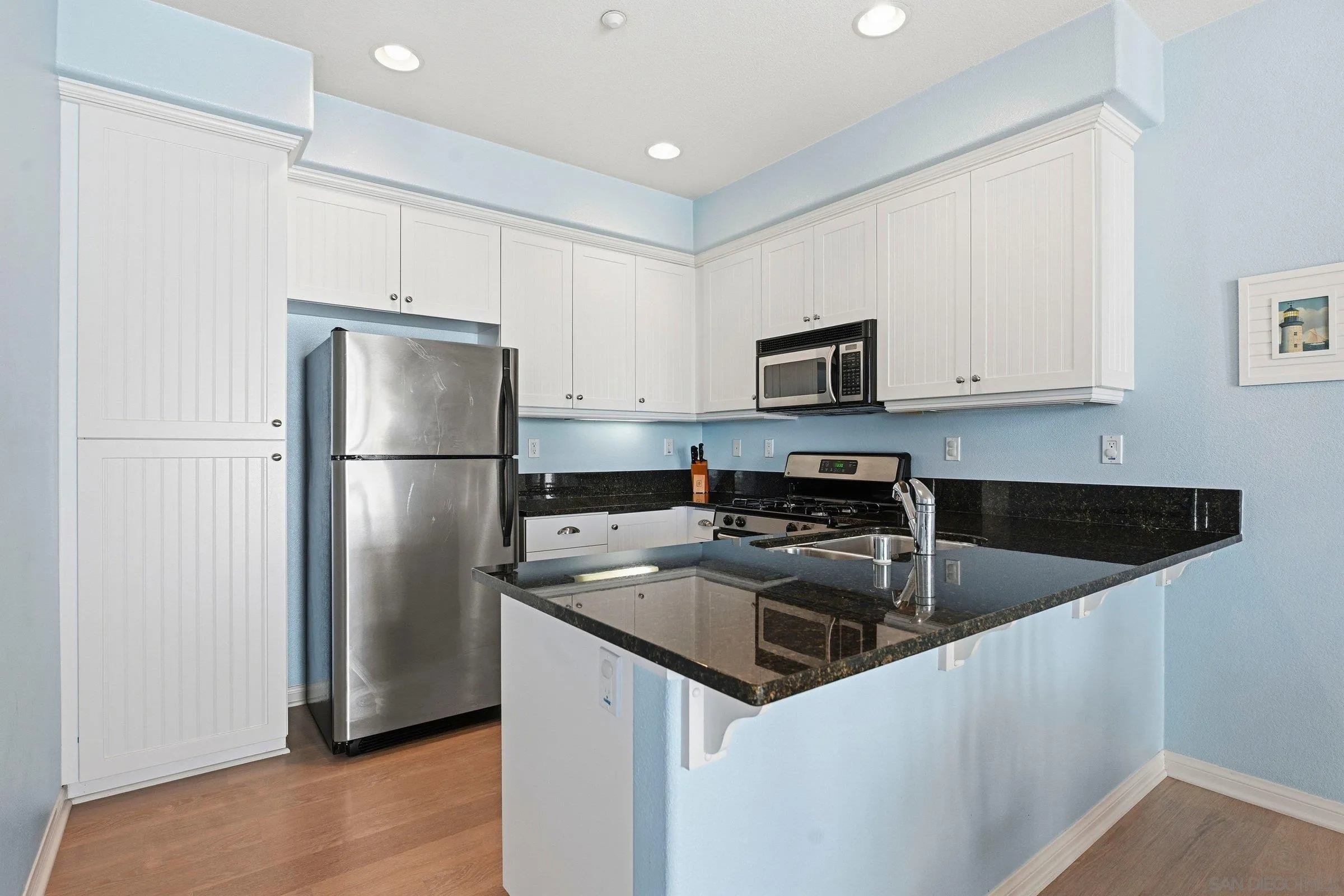 845 Harbor Cliff Way, Unit 305 Oceanside, CA 92054 - Photo 14 of 31 a kitchen with a refrigerator a microwave a sink and cabinets