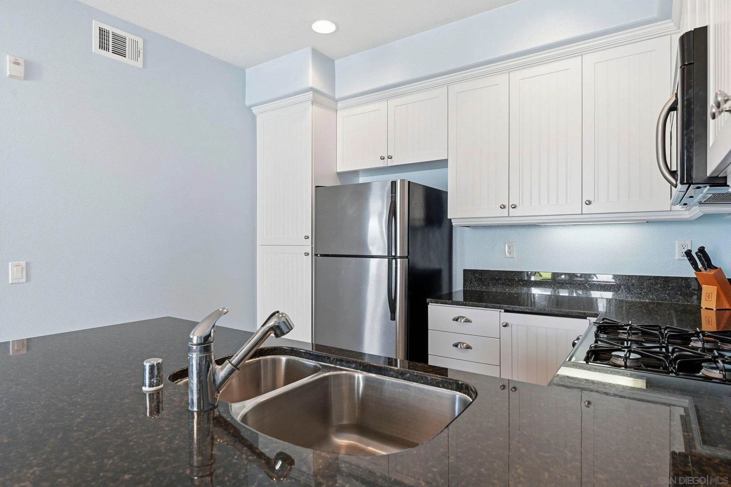 845 Harbor Cliff Way, Unit 305 Oceanside, CA 92054 - Photo 17 of 31 a kitchen with a sink a refrigerator and cabinets