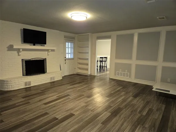 an empty room with wooden floor fireplace and windows