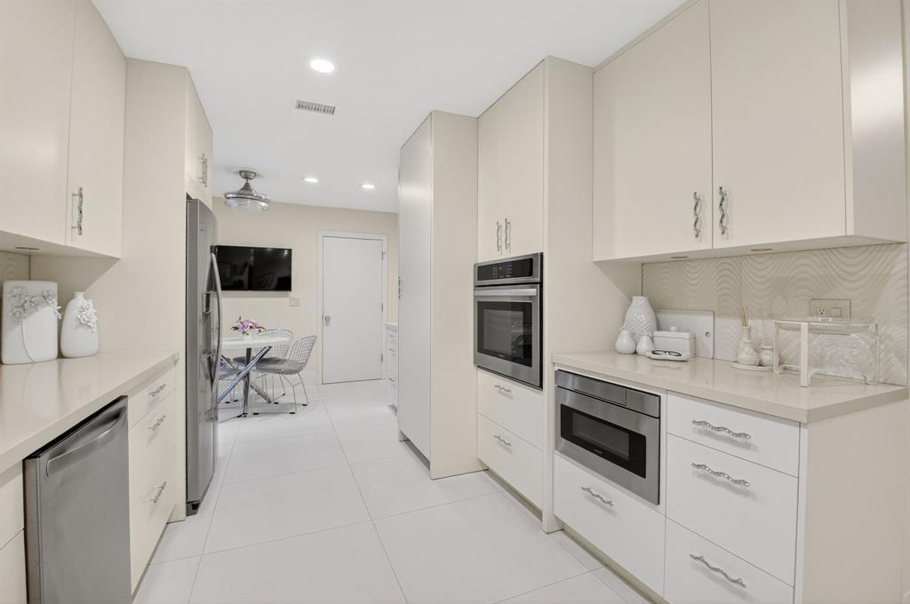 19452 Waters Reach Lane, Unit 305 Boca Raton, FL 33434 - Photo 5 of 77 a kitchen with granite countertop white cabinets and white appliances