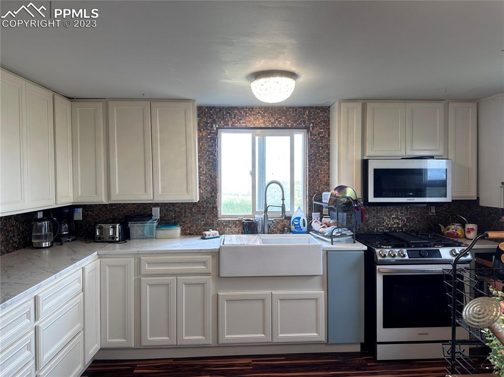 30595 Fred View Road Yoder, CO 80864 - Photo 3 of 21 a kitchen with stainless steel appliances granite countertop a sink a stove a microwave a sink and cabinets