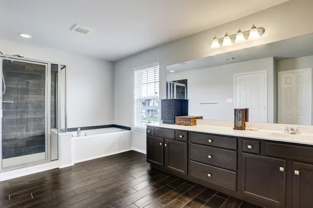 a bathroom with a tub sink double vanity and a mirror
