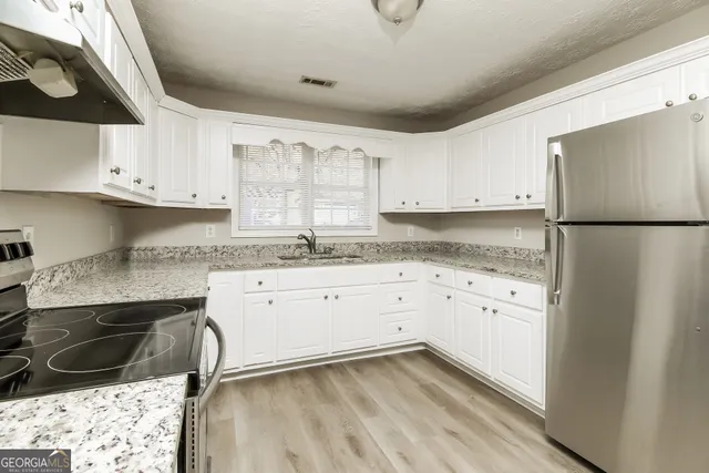 a kitchen with granite countertop white cabinets and white appliances