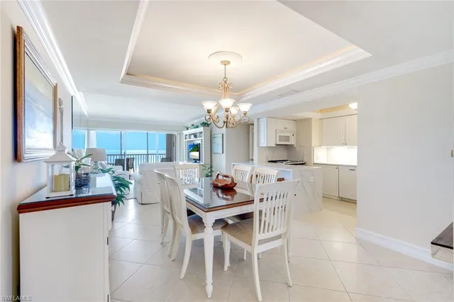 a dining room with furniture a chandelier and kitchen view
