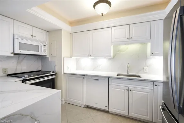 a kitchen with white cabinets and white appliances